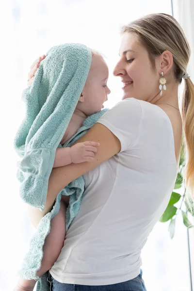 Happy young mother hugging her baby boy covered in blue towel af — Stock Photo, Image