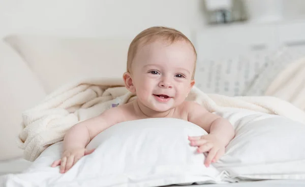 Glada leende pojke liggande på stor säng — Stockfoto