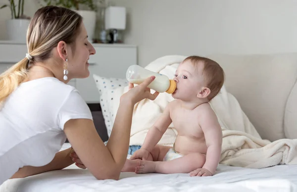 Retrato del niño sentado en la cama y comiendo leche del biberón — Foto de Stock