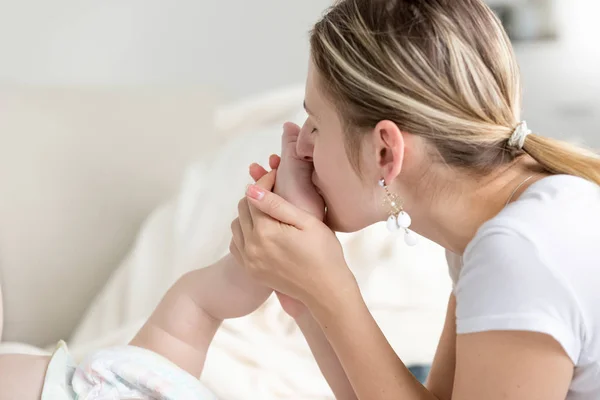 Close-up van mooie jonge moeder baby voet kussen — Stockfoto