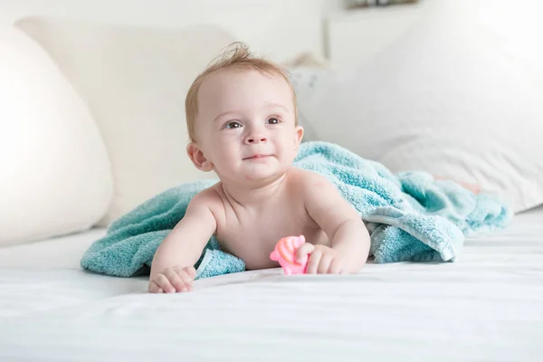 9 mois bébé sur le lit sous une serviette bleue après avoir pris une douche — Photo