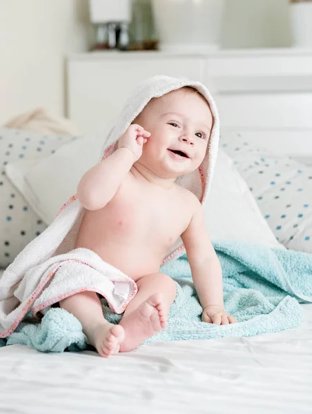9 månader gammal baby pojke sitter på sängen omfattas i handduk efter badet — Stockfoto