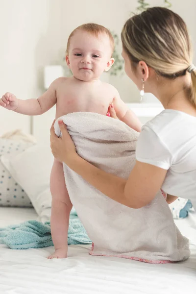 Young mother wiping her baby boy with towel on bed — Stock Photo, Image
