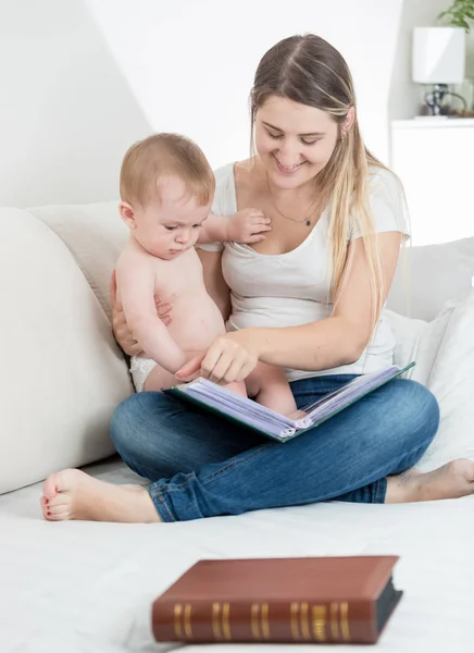 Sorrindo mãe mostrando imagens no livro antigo para ela 9 meses de idade ba — Fotografia de Stock