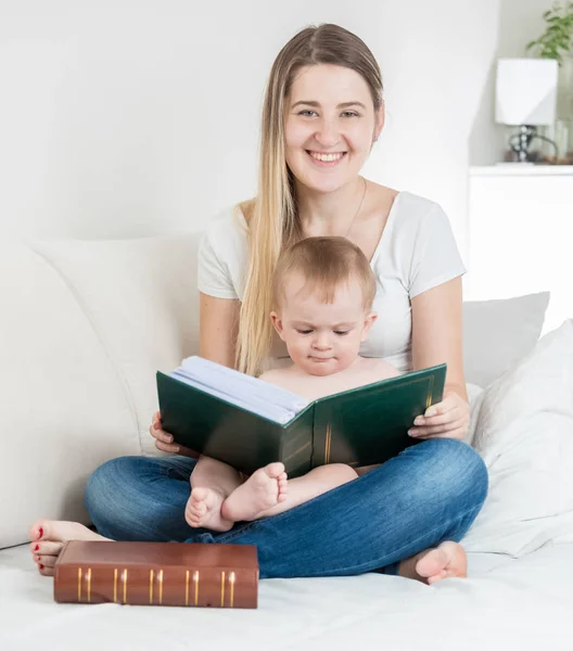 Felice giovane madre e il suo bambino in posa con grande libro — Foto Stock