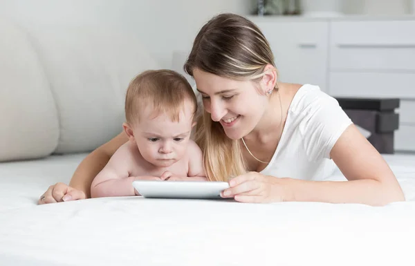 Gülümseyen anne ve bebek oğlum yalan olarak tablet Pc kullanma portre — Stok fotoğraf