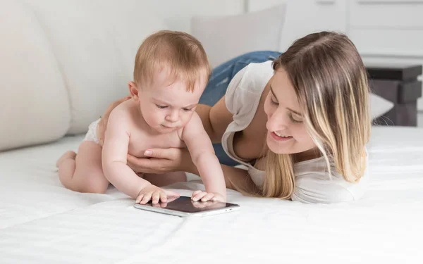 Портрет улыбающейся матери, играющей с ребенком на планшете — стоковое фото