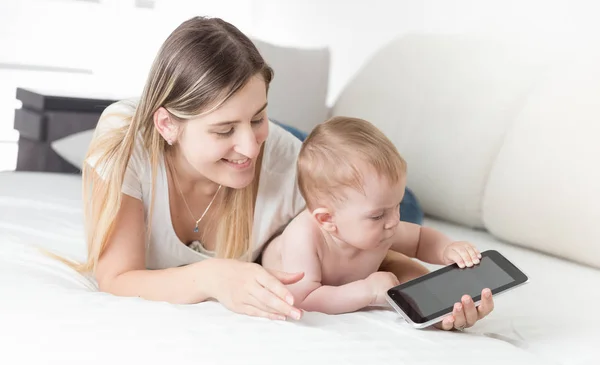Счастливая мать с ребенком просматривает интернет на планшетном компьютере — стоковое фото