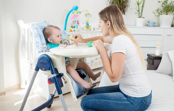 Yüksek sandalyede oturan ve yulaf lapası yemek bebek çocuk portresi — Stok fotoğraf