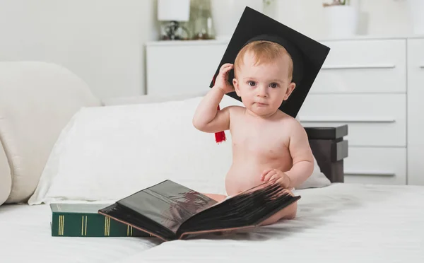 Menino inteligente na formatura cap posando com livros — Fotografia de Stock