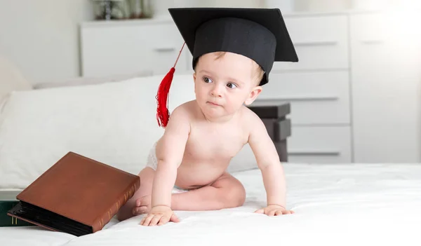 Lindo bebé niño en negro graduarse tapa asientos en el sofá — Foto de Stock