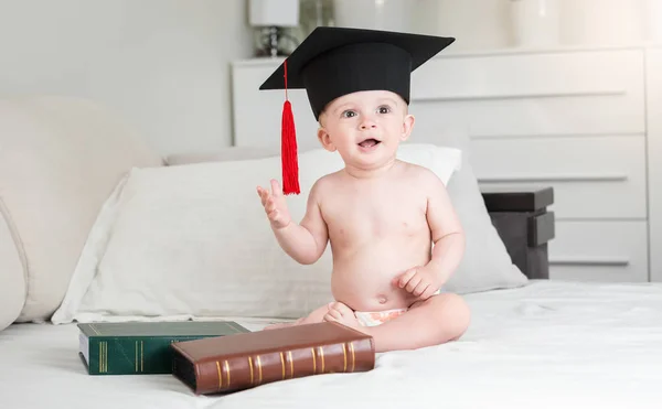 Lustiger kleiner Junge in Windeln mit schwarzer Abschlussmütze — Stockfoto