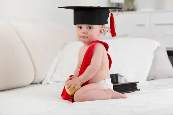 Carino il bambino con il berretto per la laurea che tiene la mela. Concetto di bambino e — Foto Stock