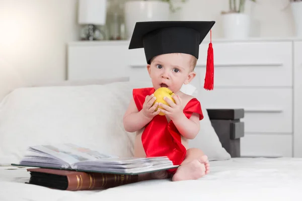 Ritratto di adorabile bambino in berretto di laurea seduto da — Foto Stock