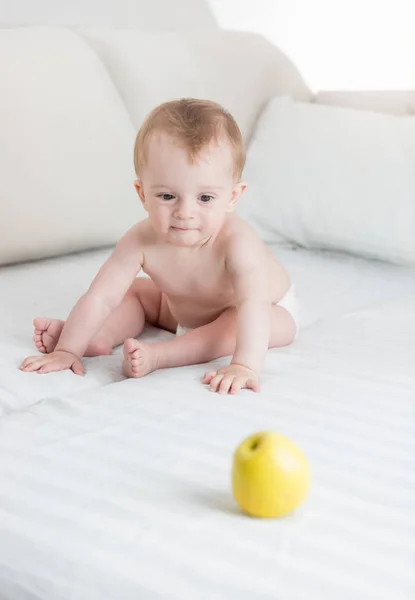 10 个月大婴儿男孩玩耍着黄色的苹果，在床上 — 图库照片