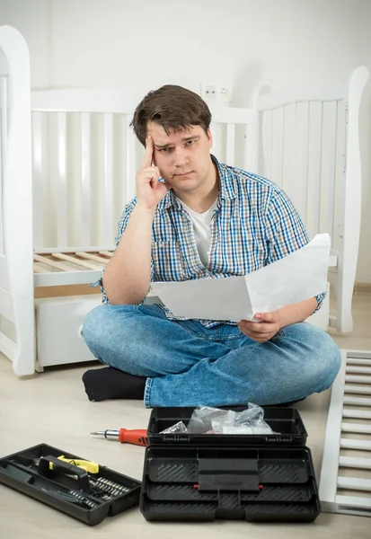 Muž sedí na podlaze a čtení komplikovaných manuál, kompletace — Stock fotografie