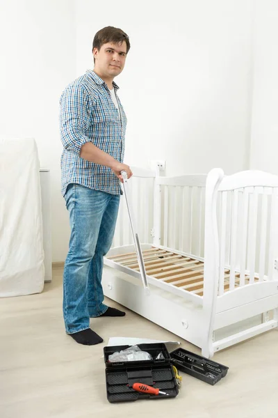 Homme à tout faire assemblant un lit bébé blanc dans un nouvel appartement — Photo