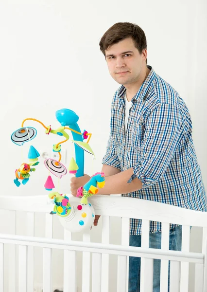 Młody ojciec szczęśliwy wyświetlone nowe zabawki karuzela w łóżeczko dla dziecka do jego s baby — Zdjęcie stockowe