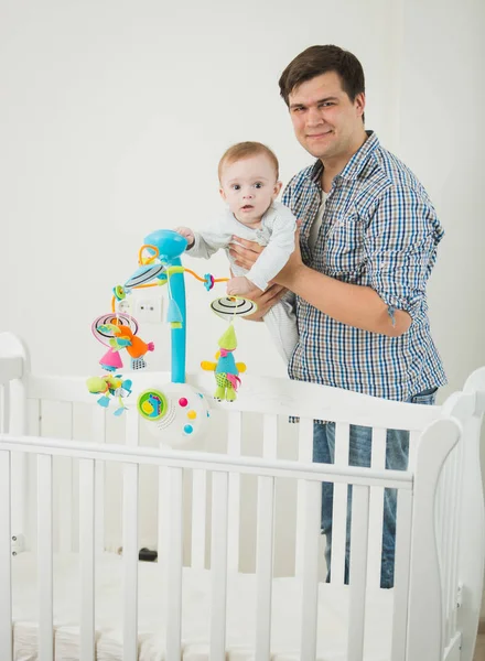 Niedlicher kleiner Junge steht im Kinderbett und spielt mit seinem Vater — Stockfoto