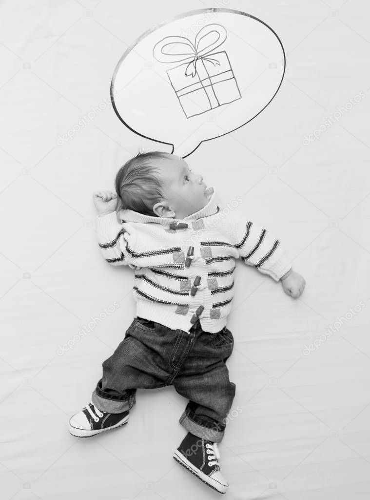 Black and white photo of cute little baby boy dreaming of presen