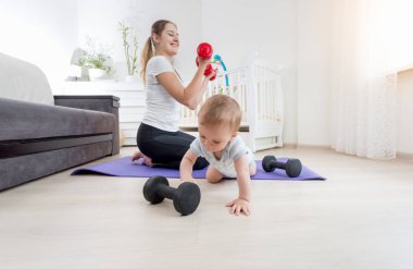 Dumbbe katta egzersiz erkek onun bebek ile annesi gülümseyerek