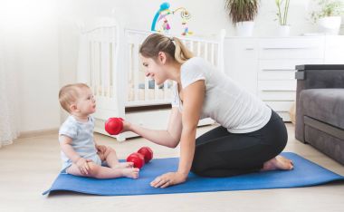 Gülümseyen anne bebeğini katta ile fiziksel egzersiz yaparak