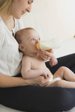 Genç anne onun bab şişe veren yatakta oturmuş portresi