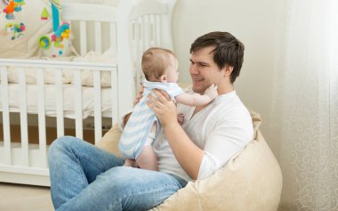 Yatak odası onun bebekle oynarken mutlu genç adam