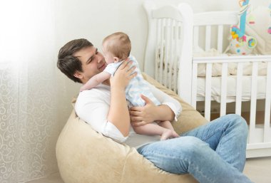 Çanta sandalyede oturan ve onun 6 m ile oynarken mutlu genç Baba