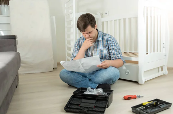 Homem confuso de montagem manual de leitura de móveis — Fotografia de Stock