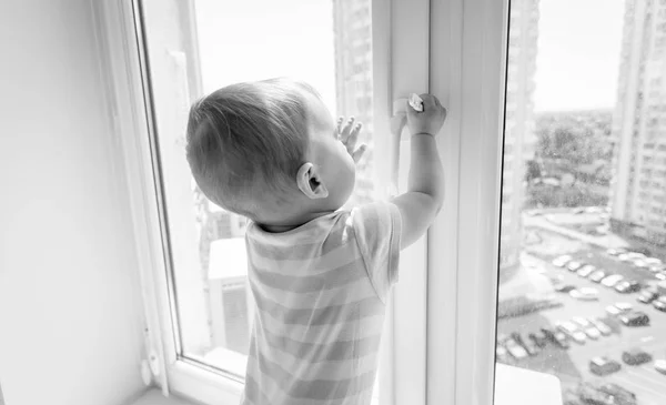 Black and white image of baby in danger. Baby boy pulling handle — Stock Photo, Image