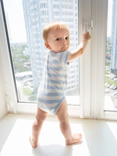 10-месячный мальчик пытается открыть окно — стоковое фото