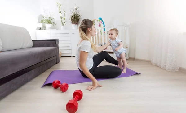 Hermosa madre sonriente con niño pequeño practicando yoga en forma — Foto de Stock