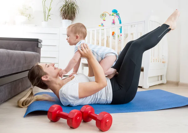 Feliz madre haciendo yoga con su bebé en el suelo en Living Roo — Foto de Stock