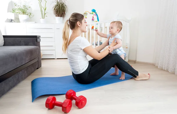Счастливая молодая мать тренируется на полу с маленьким мальчиком — стоковое фото