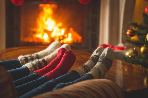 Pies femeninos y masculinos en calcetines de lana que se calientan en la chimenea en col rizada — Foto de Stock