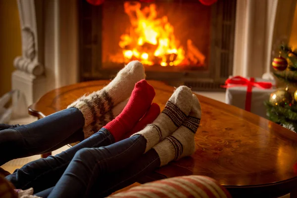 Männliche und weibliche Füße in Wollsocken wärmen sich am brennenden Kaminfeuer — Stockfoto
