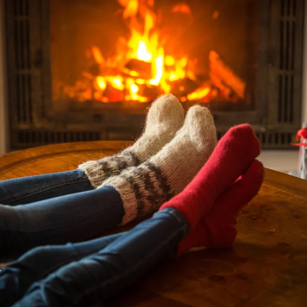 Family wearing socks sitting in chalet by burning fireplace — Stock Photo, Image