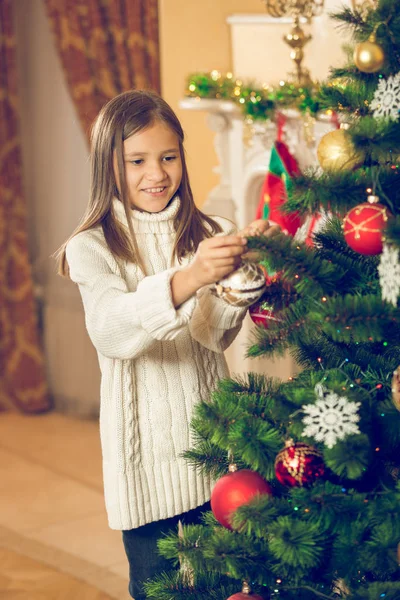 Vrolijke mooi meisje versieren kerstboom met kerstballen — Stockfoto