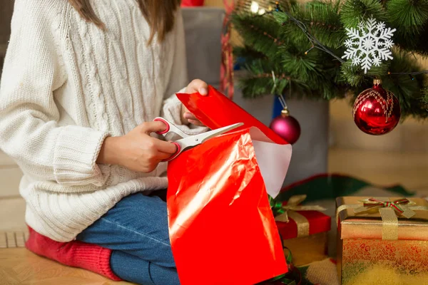 Noel ağacının altında oturan ve bilim ile kırmızı kağıt kesme kız — Stok fotoğraf