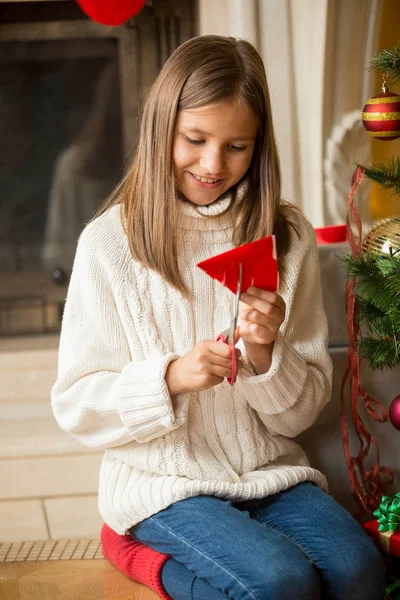 Meisje snijden papier sneeuwvlokken voor decoratie op Kerstmis — Stockfoto