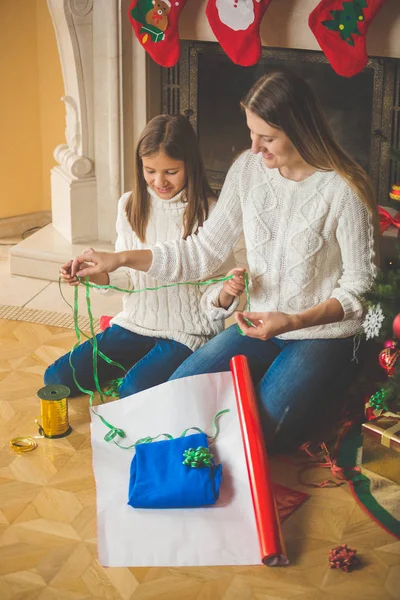 Happy family wrapping Christmas presents at fireplace — Stock Photo, Image
