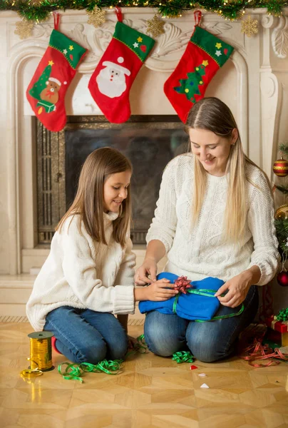 Lycklig mor och dotter som sitter på golvet vid spis och pack — Stockfoto