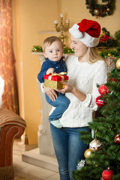 Porträtt av glad ung mamma ge presentförpackning till hennes baby på Ch — Stockfoto