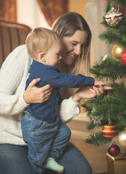 Femme souriante décorant l'arbre de Noël avec son 10 mois b — Photo