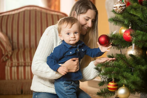 Mor med sin 10 månader gamla baby pojke dekorera julgran — Stockfoto