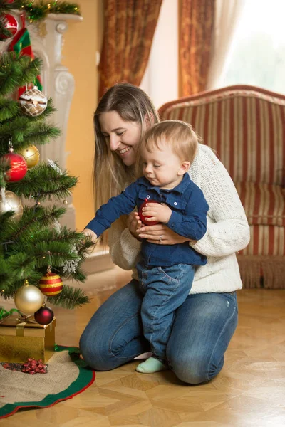 Madre enseñando a su hijo cómo decorar el árbol de Navidad con — Foto de Stock