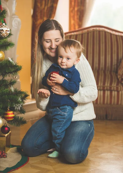 Mère et bébé garçon souriants décorant l'arbre de Noël avec baubl — Photo