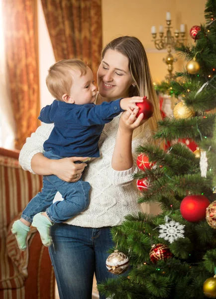 Glad ung kvinna med hennes baby son dekorera julgran — Stockfoto