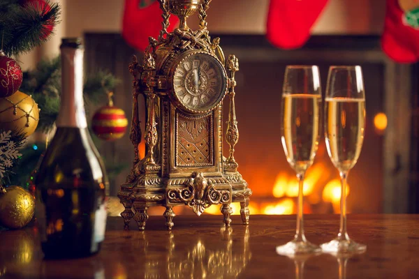 Два бокала шампанского на столе рядом со старыми часами показывают 12 часов. — стоковое фото